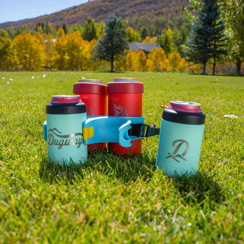 Colorful insulated drink containers with a holder on grass with trees in the background